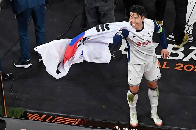 태극기 두른 ‘캡틴 SON’…유로파 우승의 환희 - 2025년 5월 21일(현지시간) 스페인 빌바오의 산 마메스 스타디움에서 열린 UEFA 유로파리그 결승전이 끝난 뒤, 토트넘 홋스퍼의 주장 손흥민이 태극기를 두른 채 환하게 웃고 있다. 이날 토트넘은 맨체스터 유나이티드를 꺾고 구단 역사상 첫 유로파리그 우승을 차지했다. AFP 연합뉴스