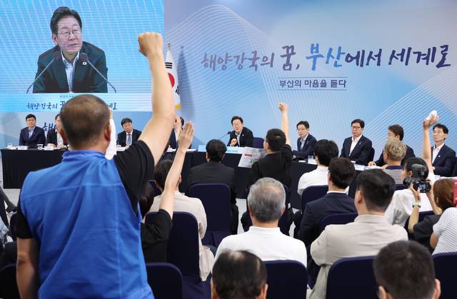 지난 7월25일 윤병철 대한민국공무원노동조합총연맹 해양수산부지부 위원장(왼쪽 파란 조끼)이 부산 부경대에서 이재명 대통령이 참석한 가운데 열린 타운홀미팅 ‘부산의 마음을 듣다’ 간담회에서 손을 들어 발언권을 요청하고 있다.<연합뉴스>
