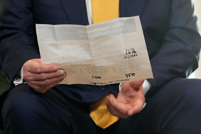 27일 영국 턴베리에서 유럽연합(EU)과의 관세 협상에 나선 도널드 트럼프 미국 대통령 손에 미국과 EU 간 투자금액과 관세율을 조정한 쪽지가 들려있다. 글자는 트럼프 대통령이 직접 적어넣은 것으로 보인다. 식별을 위해 좌우 반전된 이미지. 턴베리(영국)=AP 연합뉴스