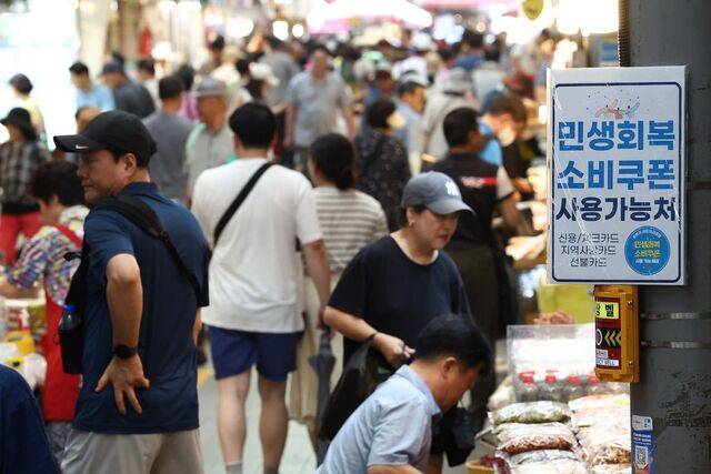 정부가 ‘민생회복 소비쿠폰’을 지급한 뒤 첫 주말인 27일 무더위에도 시민들로 북적이는 서울 동대문구 청량리종합시장에 소비쿠폰 사용 안내문이 붙어 있다. 연합뉴스