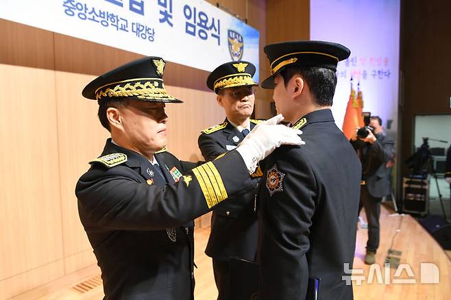 [서울=뉴시스] 지난 3월 21일 충남 공주 중앙소방학교 대강당에서 제30기 소방간부후보생 졸업 및 임용식이 열린 가운데 허석곤 소방청장이 졸업생에게 계급장을 달아주고 있다. (사진=소방청 제공) 2025.3.21 photo@newsis.com