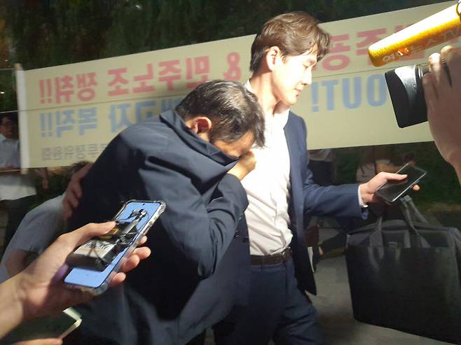 김건희 여사의 오빠 김진우 씨가 25일 오후 11시쯤 김건희 특검팀(특별검사 민중기) 조사를 마치고 옷깃으로 얼굴을 가린 채 변호인 부축을 받으며 취재진을 피해 걸어가고 있다. (사진=뉴스1)