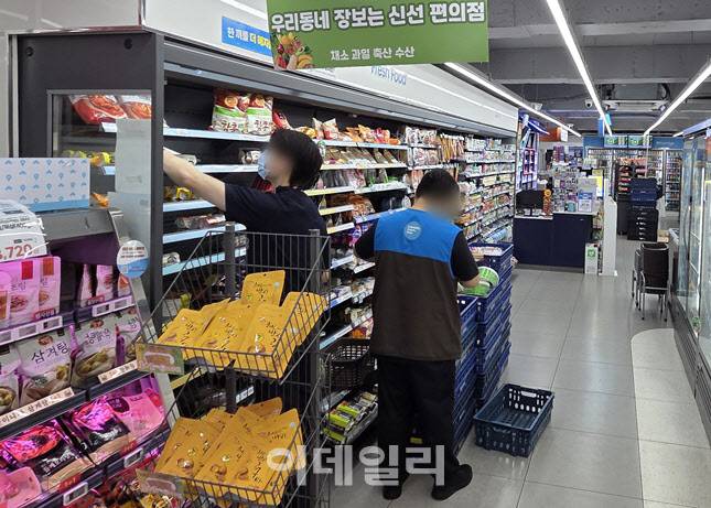 서울의 한 GS25 신선특화매장에서 한 고객(왼쪽)이 제품을 고르고, 직원이 신선식품 진열 작업을 하고 있다. 이 매장은 과일·채소·정육 등 구색을 갖춘 ‘신선강화매장’이다. (사진=한전진 기자)