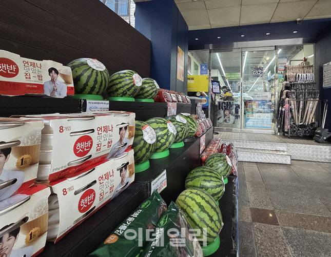 한 편의점 입구에 수박, 햇반, 계란 등 생필품과 제철 과일이 전면 진열돼 있다. 민생쿠폰 지급 이후 식재료 수요가 늘며 고가 품목까지 매대 구성에 포함되고 있다. (사진=한전진 기자)