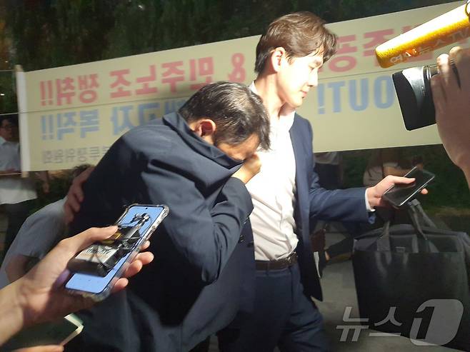 김건희 여사의 오빠 김진우 씨가 25일 오후 11시쯤 김건희 특검팀(특별검사 민중기) 조사를 마치고 옷깃으로 얼굴을 가린 채 변호인 부축을 받으며 취재진을 피해 걸어가고 있다. 2025.7.28/뉴스1 ⓒ News1 정윤미 기자