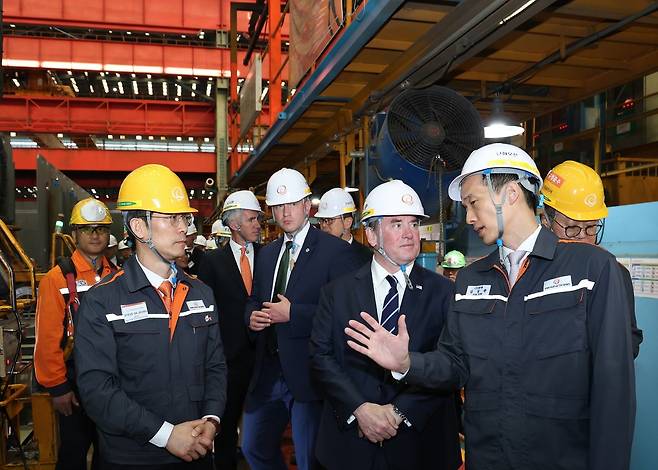 Hanwha Group Vice Chairman Kim Dong-kwan (right) introduces the ship block assembly plant to John P. Phelan (second from right), US secretary of the navy, at Hanwha Ocean’s shipyard in Geoje, South Gyeongsang Province, May 30. (Hanwha Ocean)