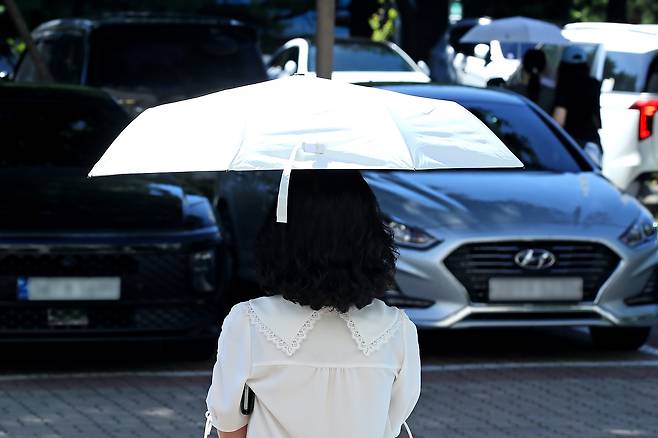 A person walks underneath the shade of a sun umbrella near a community center in Daegu on July 28. [NEWS1]