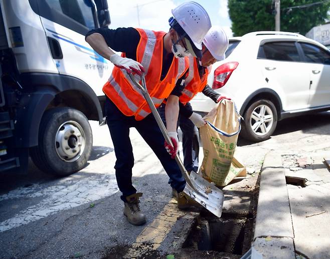 14일 오후 광주 서구 양동 인근에서 서구청 관계자들이 빗물받이 내 쓰레기를 치우고 있다. 2025.07.14. lhh@newsis.com /사진=뉴시스