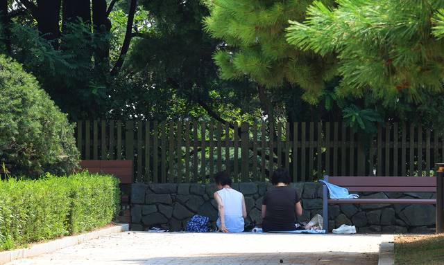 전국 대부분 지역에 폭염경보가 내려진 25일 인천 중구 자유공원에서 시민들이 나무 그늘 아래 더위를 식히고 있다. 연합뉴스