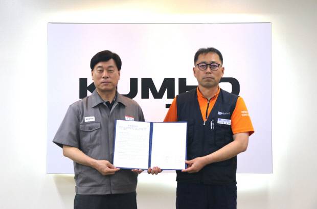 김명선(왼쪽) 금호타이어 생산기술총괄 부사장과 황용필 금호타이어지회 대표 지회장이 노사 특별합의문을 들고 사진을 찍고 있다. <금호타이어 제공>