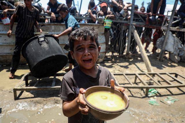 24일 가자지구 가자시티 자선 급식소에서 한 팔레스타인 어린이가 구호 음식을 받아들고 있다. 가자시티=신화 뉴시스