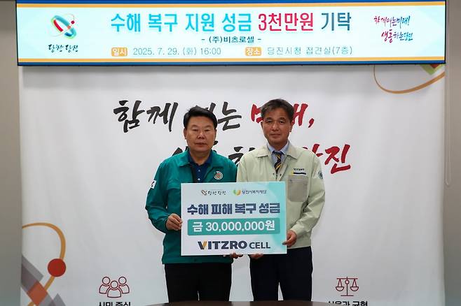 오성환 당진시장(왼쪽)과 김길중 비츠로셀 경영전략관리본부장이 수해 피해 복구 성금 푯말을 들고 기념 사진을 찍고 있다. 당진시 제공