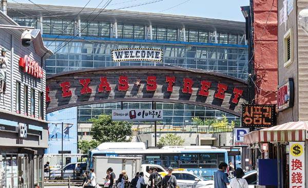 30일 부산 동구 ‘텍사스 거리’를 찾은 관광객들이 아치형 조형물 아래를 지나고 있다. 부산시와 동구는 ‘부산역 도시비우기 시범사업’을 통해 이 조형물을 철거하고, 거리 명칭 변경을 추진한다.  이원준 기자 windstorm@kookje.co.kr
