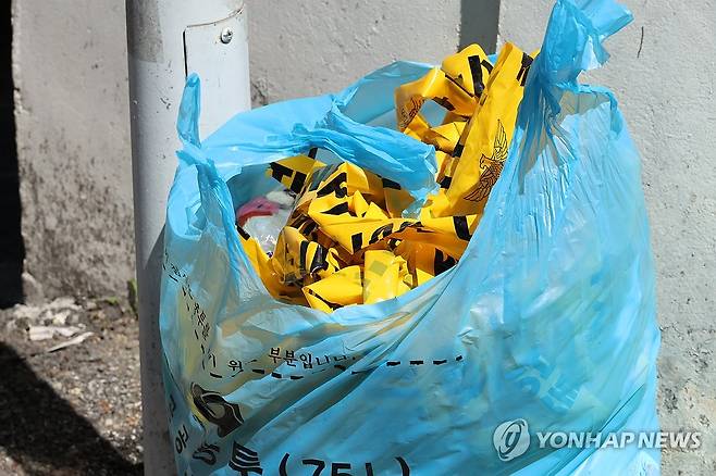 흉기 살인 발생한 대전 서구 괴정동 주택가 (대전=연합뉴스) 강수환 기자 = 29일 낮 12시 8분께 대전 서구 괴정동 주택가에서 한 남성이 30대 여성을 흉기로 찌르고 도주했다. 경찰은 피해 여성의 전 연인으로 추정되는 20대 남성 용의자를 쫓고 있다. 사진은 현장에 쳐놨던 폴리스라인이 쓰레기봉투에 버려져 있는 모습. 2025.7.29 swan@yna.co.kr