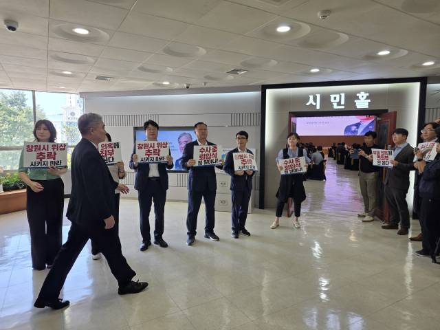 창원시 조명래 제2부시장이 31일 퇴임식에 참석하기 위해 복도를 걸어가고 있다. 퇴임식장 앞에서 여당 시의원들이 수사 중 퇴임을 규탄하는 시위를 진행했다.