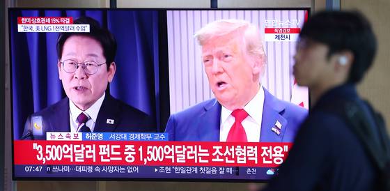 한국과 미국의 관세협상이 타결된 31일 서울역 대합실에서 한 시민이 관련 뉴스가 나오는 TV 앞을 지나고 있다. 연합뉴스