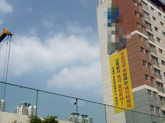 A protest banner near the KT Cloud data center in Guro District, Seoul, demands an immediate halt to construction, citing health concerns such as electromagnetic wave exposure. [LEE JAE-LIM]