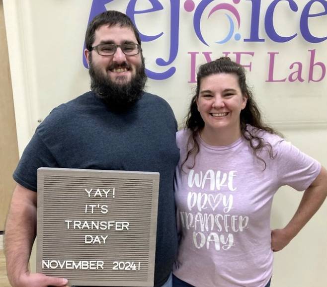 린지 피어스(오른쪽)과 팀이 지난해 11월 테네시주 녹스빌의 체외수정 클리닉 리조이스 퍼틸리티에서 이식한 날을 기념하는 팻말을 들고 활짝 웃고 있다/사진=MIT 테크놀로지 리뷰