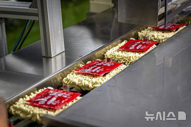 [밀양=뉴시스] 삼양식품 밀양2공장에서 불닭볶음면을 생산하는 모습. 모든 공정을 거친 면 상단에 소스를 투입하는 '포장'이 자동화로 이뤄지고 있다. (사진= 삼양식품 제공) photo@newsis.com