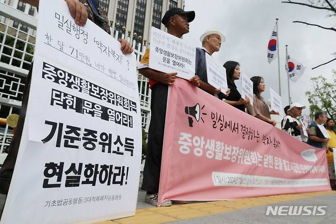 [서울=뉴시스] 김명원 기자 = 기초법바로세우기 공동행동 등 참석자들이  지난해 7월 25일 오전 서울 종로구 정부서울청사 앞에서 정부 중앙생활보장위원회에 기준중위소득 현실화와 부양의무자기준 완전 폐지를 요구하는 민중생활보장위원회 기자회견을 하고 있다. 2024.07.25. kmx1105@newsis.com