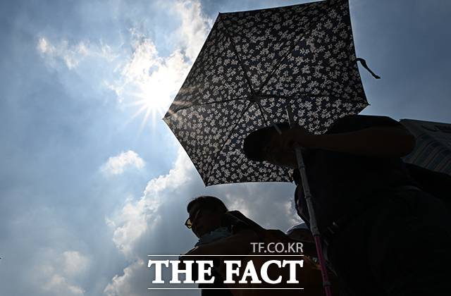 전국 대부분 지역에 발효된 폭염 특보로 극한 더위가 이어지고 있다. 탄소 절약에 앞장서며 냉방이 제한된 국회에선 높아진 실내 온도로 곡소리가 새어 나오고 있다. 사진은 지난 28일 오전 서울 종로구 세종대로에서 시민이 양산을 쓰고 걷고 있는 모습. /박헌우 기자