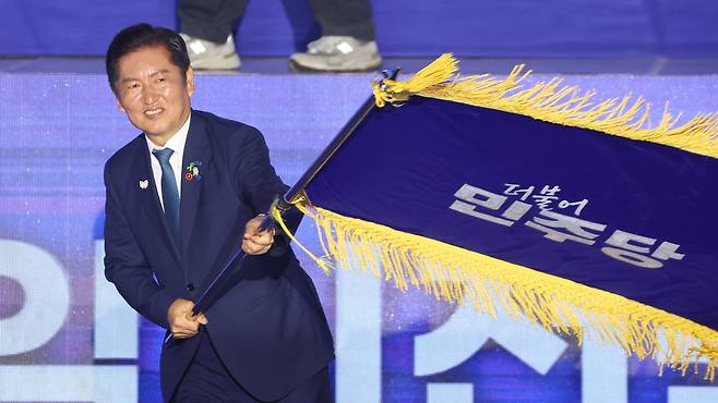 더불어민주당 정청래 신임 당대표가 2일 고양 킨텍스에서 열린 전국당원대회에서 김병기 당대표 직무대행 겸 원내대표로부터 받은 당기를 흔들고 있다./연합뉴스
