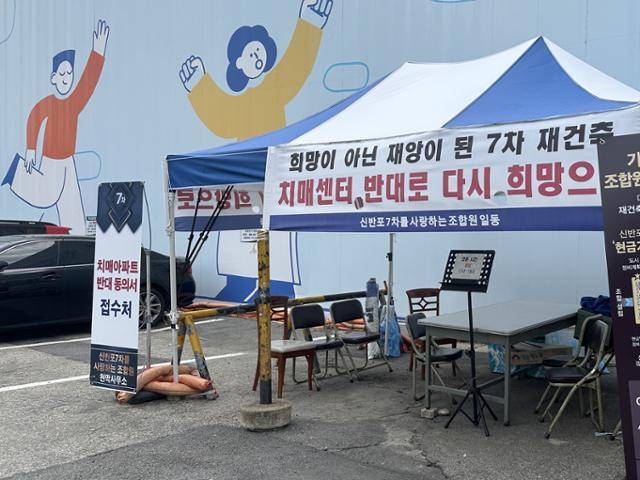 한신7차 아파트 입구에 들어선 데이케어센터(노인돌봄시설) 설치 반대 동의서 접수처. 노인돌봄시설을 설치하지 않아도 현금 기부채납으로 재건축이 가능하다는 입간판도 설치됐다. 김민호 기자