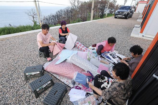 마을에 생필품을 싣고 온 상인이 오자 마을 어른들이 자리에 앉아 물건을 고르고 있다. 전민규 기자