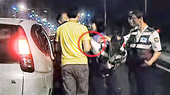 박철씨가 경찰관의 팔을 꺾었는지 여부를 판단할 수 있는 유일한 증거인 영상. 두 사람의 손 부분은 노란옷을 입은 박씨의 아들에 가려져 팔을 꺾었는지 여부를 두고 재판에서 공방이 일었다. 사진 박철씨