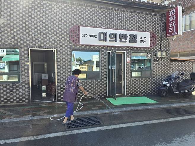 대의반점 배영자 사장이 가게 앞 물을 뿌리며 장사 개시를 준비하고 있다. 의령군 제공