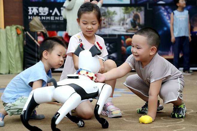 지난 3일 중국 산둥성 둥잉에서 열린 인공지능 로봇 전시회에서 어린이들이 로봇개를 만지고 있다. 신화 연합뉴스