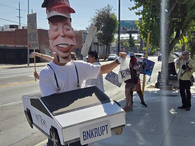 일론 머스크 테슬라 최고경영자(CEO)의 정치 행보를 비판하는 시위대들이 3일(현지시간) 로스앤젤레스에 문을 연 '테슬라 다이닝' 앞에서 시위하고 있다. 김인엽 특파원