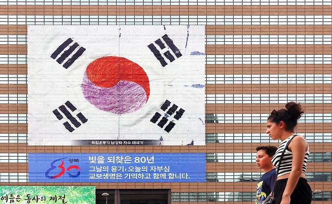 교보생명이 서울 광화문 본사 외벽에 광복 80주년을 맞아 '남상락 자수 태극기'를 래핑했다고 4일 밝혔다. 태극기는 가로 31m, 세로 31m 크기로 이달 17일까지 볼 수 있다. 이 태극기는 독립운동가 남상락 선생이 1919년 충남 당진에서 펼쳐진 4·4 독립만세운동에 쓰기 위해 만들었다. 아내 구홍원 여사가 직접 짠 명주에 손바느질로 자수를 놓아 만든 것으로 알려졌다. 1949년 태극기 표준화 이전에 만들어져 태극기의 4괘 중 '감'과 '리'의 위치가 다르다. 외국인들이 지난 3일 태극기 앞을 지나고 있다. 이충우 기자
