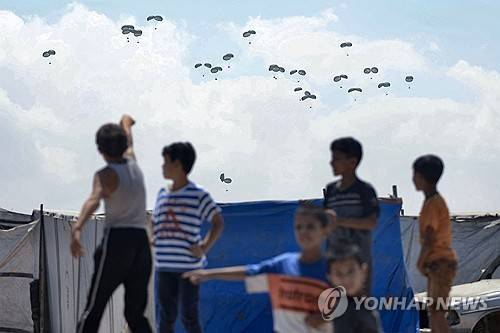 가자 남부 라파에서 어린이들이 구호품이 하늘에서 떨어지는 걸 지켜보고 있다.  [AFP 연합뉴스 자료사진. 재판매 및 DB 금지]