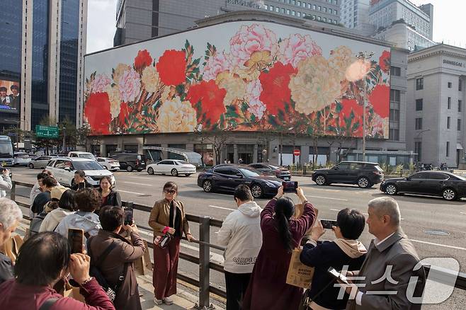 신세계스퀘어에서 상영하는 K-컬처 콘텐츠를 보며 즐기는 외국인 관광객 모습. (신세계백화점 제공. 재판매 및 DB 금지) 2025.4.13/뉴스1