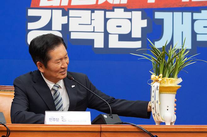 李대통령 ‘축하 난’ 바라보는 정청래 정청래 더불어민주당 대표가 4일 국회에서 우상호 대통령실 정무수석에게 이재명 대통령의 축하 난을 받은 뒤 화분을 살펴보고 있다. 정 대표는 “이 대통령이 전당대회 직후 직접 저한테 전화로 격려해주셨고 축하 난을 선물해주시니 기쁨이 두 배”라고 했다./뉴스1