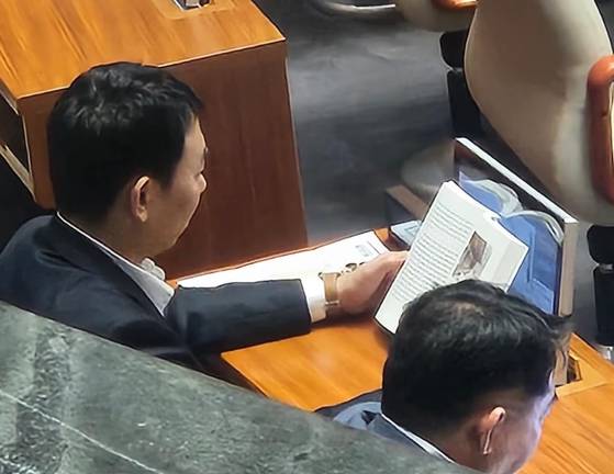 신동욱 국민의힘 의원이 4일 서울 여의도 국회에서 열린 제427회 국회(임시회) 3차 본회의에 상정된 방송법 일부개정법률안(대안)에 대한 무제한 토론(필리버스터)을 하고 있는 가운데 김용민 더불어민주당 의원이 책을 보고 있다. 뉴스1