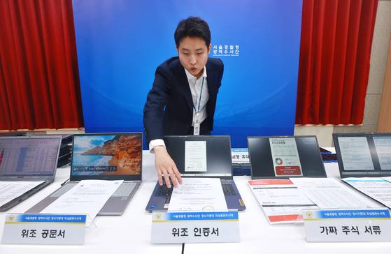 5일 서울 마포구 서울경찰청 광역수사단에서 남철안 서울경찰청 광역수사단 형사기동대 피싱범죄수사계 관계자가 '주식 거래 빙자' 신종 피싱조직 검거 관련 브리핑에 앞서 가짜 주식 서류, 위조 인증서 등을 나열하고 있다. 연합뉴스