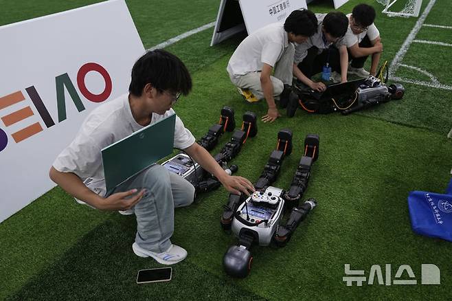[베이징=AP/뉴시스] 4일(현지 시간) 중국 베이징에서 '2025 세계 휴머노이드 로봇 게임'을 앞두고 언론 공개 행사가 열린 가운데 부스터 휴머노이드 로봇 개발자들이 시스템 점검을 하고 있다. 오는 14일부터 17일까지 열리는 이 행사에는 축구를 비롯해 달리기, 격투, 댄스 등 실제 사람의 경기와 유사한 종목이 포함된 것으로 알려졌다. 2025.08.05.