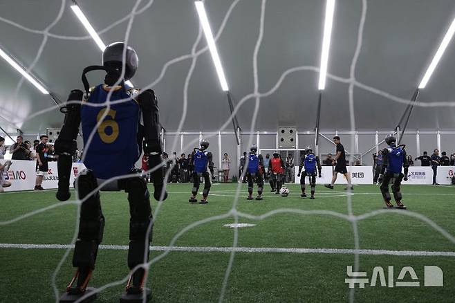 [베이징=AP/뉴시스] 4일(현지 시간) 중국 베이징에서 '2025 세계 휴머노이드 로봇 게임'을 앞두고 언론 공개 행사가 열린 가운데 부스터 휴머노이드 로봇들이 축구 시범 경기로 기술을 선보이고 있다. 오는 14일부터 17일까지 열리는 이 행사에는 축구를 비롯해 달리기, 격투, 댄스 등 실제 사람의 경기와 유사한 종목이 포함된 것으로 알려졌다. 2025.08.05.