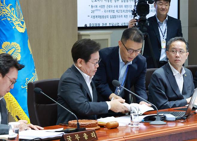 이재명 대통령이 지난달 29일 서울 용산 대통령실 청사에서 열린 국무회의에서 국무위원들과 중대재해 근절대책 토론을 하며 대통령실 참모진으로부터 관련 법령 자료를 받고 있다. 연합뉴스