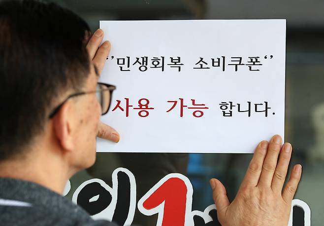 지난달 22일 오후 대구 중구의 한 음식점 주인이 출입문에 민생회복 소비쿠폰 사용 가능 안내문을 붙이고 있다. /뉴스1