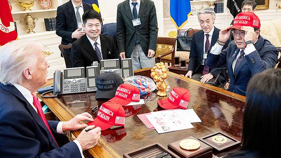 지난 4월 관세협상을 위해 미국 백악관을 방문한 아카자와 료세이 경제재생담당상이 도널드 트럼프 대통령으로부터 건네받은 모자를 착용해보고 있다. 로이터=연합뉴스