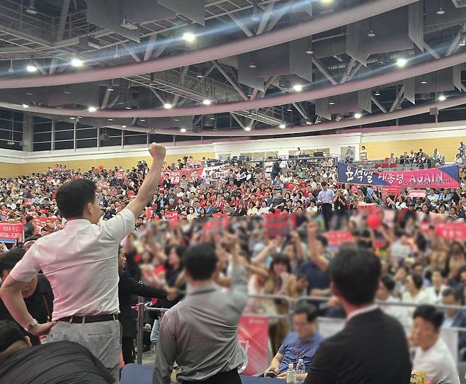 8일 대구 엑스코에서 열린 국민의힘 전당대회 합동연설회에서 조경태 당대표 후보의 연설 도중 의자 위에 올라 청중들에게 자신의 팔을 들어보이는 유튜버 전한길씨. 이에 호응하는 지지자들이 든 현수막에는&nbsp;‘윤석열 대통령 AGAIN’이라고 적혀 있다. 이지안 기자