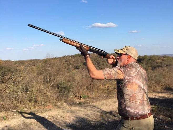 사냥 도중 조준 자세를 취한 애셔 왓킨스. 위장색 사냥복을 입고 더블 배럴 산탄총을 든 채 들짐승을 겨냥하는 모습이다. 그는 평생을 사냥과 함께한 열정적인 헌터였으며, SNS를 통해 이 같은 사진을 자주 공유해 왔다. 출처=애셔 왓킨스 아웃도어스 페이스북