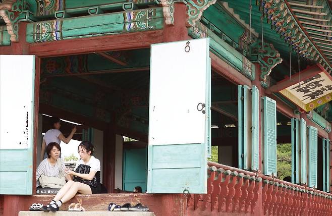 < “K컬처 즐기자” > 8일 경기 수원시 팔달구 수원화성 화홍문을 찾은 중국인 관광객들이 전각 마루에 앉아 휴식을 취하고 있다. 수원화성은 지난해 방영된 인기 드라마 ‘선재 업고 튀어’의 배경으로 등장해 한국 문화와 역사를 즐기러 온 외국인의 인기 여행 코스가 됐다.  /문경덕 기자
