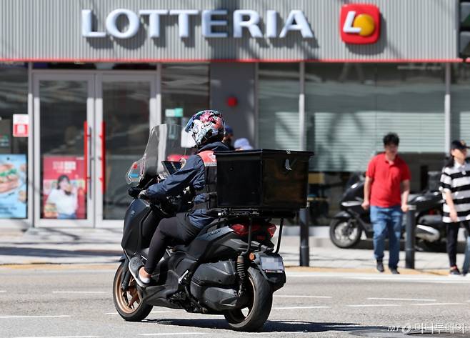 [서울=뉴시스] 이영환 기자 = 23일 서울 시내의 한 롯데리아 앞에서 배달기사들이 이동하고 있다.  롯데GRS가 운영하는 버거 프랜차이즈 롯데리아는 오는 24일부로 오프라인 매장과 배달 서비스의 가격을 분리 운영하기로 결정했다고 23일 밝혔다. 롯데리아 측은 "배달 플랫폼 주문 유입 시 배달 수수료·중개료·배달비 등 제반 비용이 매출 대비 평균 약 30%를 차지하고 있다"며 "무료 배달 서비스 도입으로 향후 발생하는 가맹점들의 비용 부담이 더욱 가중될 것으로 예측되돼 수익성 악화가 예상 된다"는 입장이다. 롯데리아 배달 서비스의 제품별 차등 가격은 단품 메뉴 700원~800원, 세트 메뉴 1300원 수준이다. 2024.09.23. 20hwan@newsis.com /사진=이영환