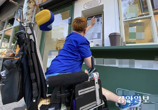 지난 8일 오후 인천시 계양구의 한 카페 앞에서 뇌병변장애인 박성호씨가 휠체어에서 불편한 몸을 일으켜 키오스크를 사용하고 있다. 2025.8.8 /조재현기자 jhc@kyeongin.com