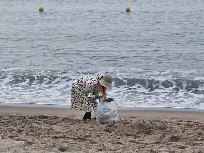 지난 9일 새벽 5시쯤부터  김씨(85)가 영덕 장사해수욕장에서 파도에 밀려온 해안가 쓰레기를 허리를 굽혀 맨손으로 봉투에 담고 있다.(영남일보 DB)