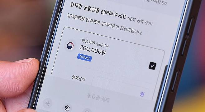 민생회복 소비쿠폰 지급 이후 첫 주말인 27일 서울 동대문구 청량리종합시장을 찾은 한 시민이 민생회복 소비쿠폰을 사용하고 있다. 사진=뉴스1